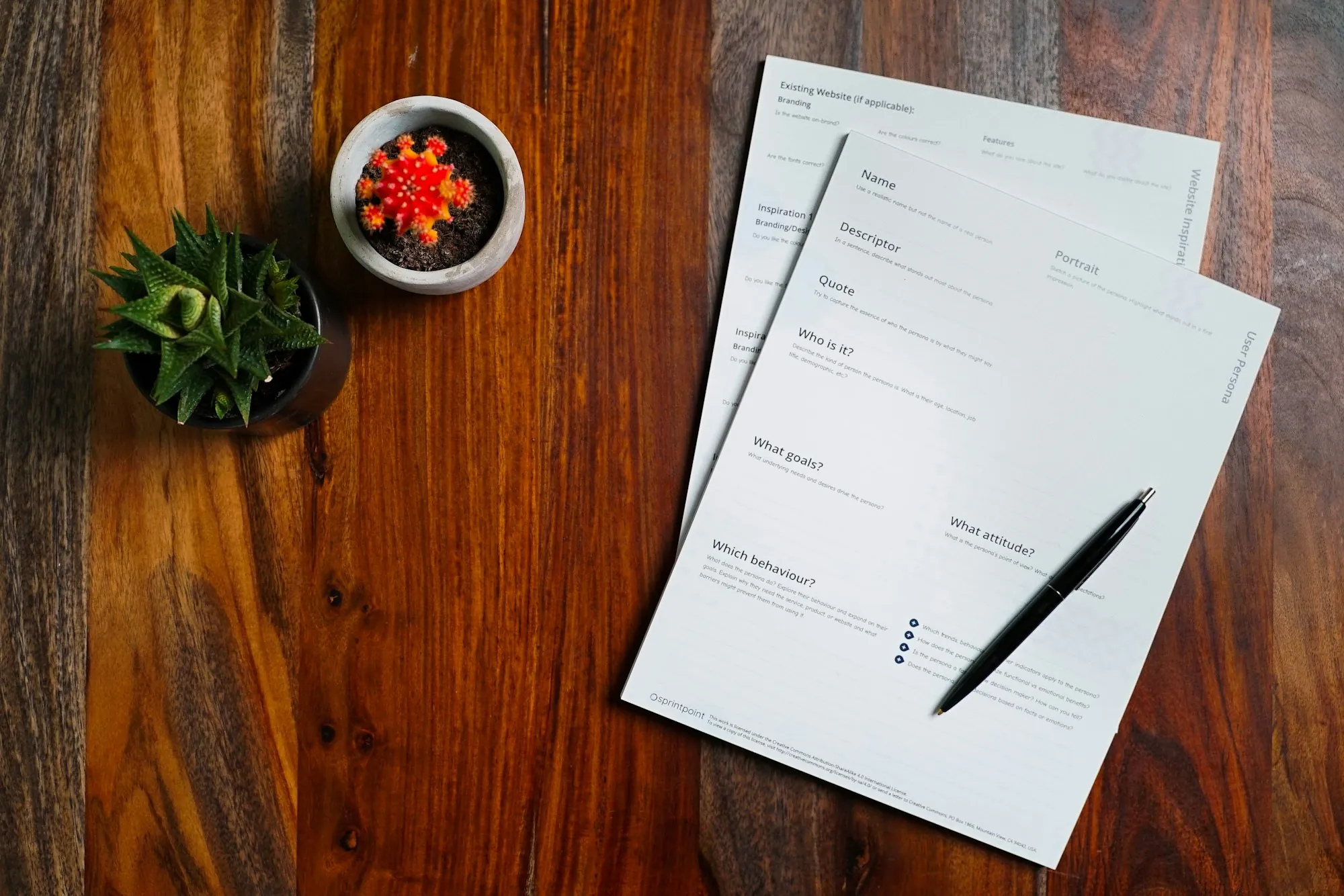 Printed pages and a pen on a dark wood desk