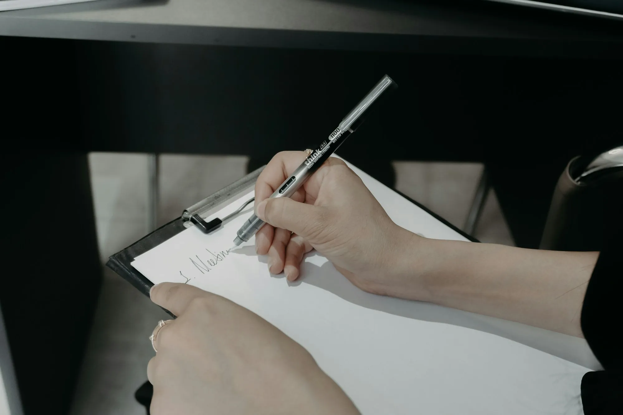 Hand writing notes on a clipboard