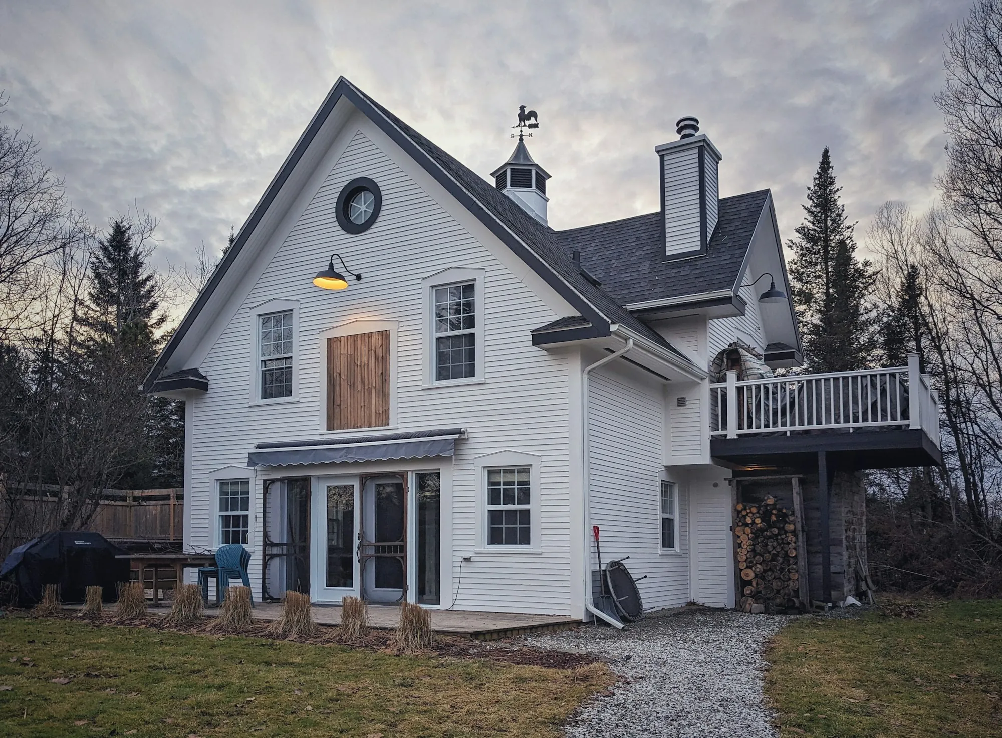 White carriage-house style home with a steep gray roof and cupola