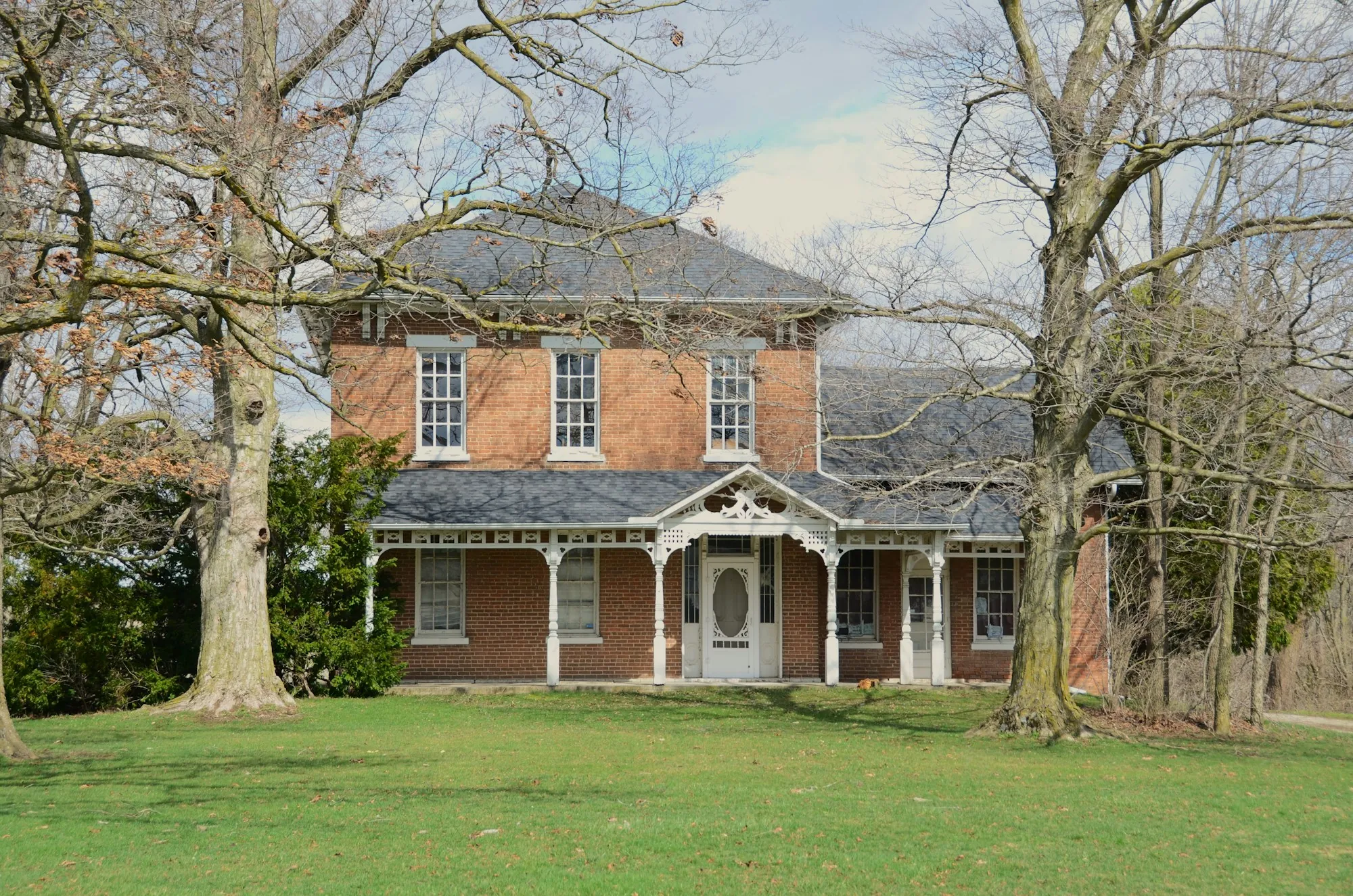 Italianate brick house with a front porch and large lawn